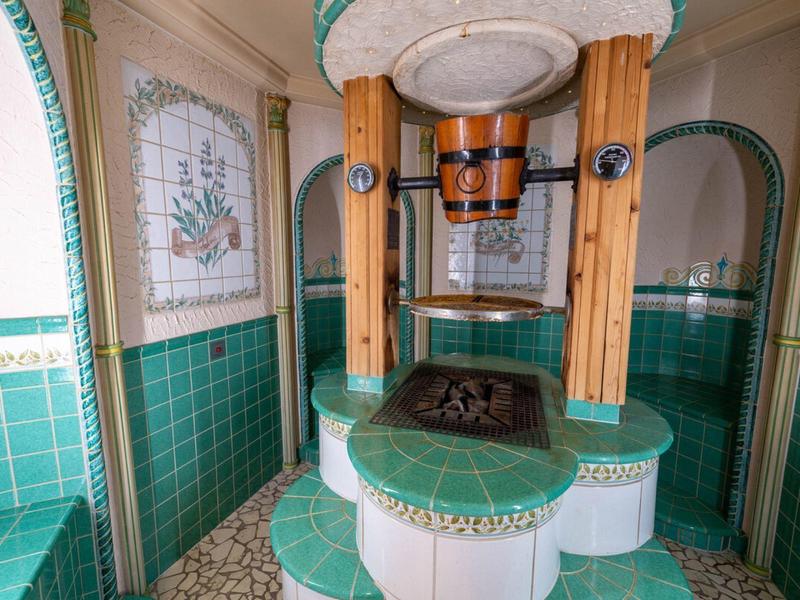 Fontana interna rotonda con piastrelle verdi e bianche e colonne di legno in un bagno.