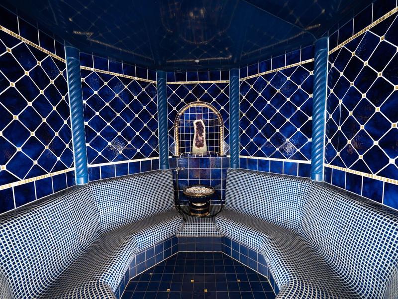 Sala vapore lussuosa con pareti piastrellate blu e fontana centrale