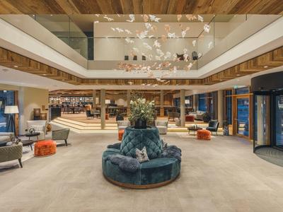 Moderner Hotel-Lobby-Bereich mit runder Sitzgelegenheit, Treppen und hellem Holzdekor.