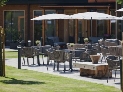 Außenbereich eines Hotels mit Tischen, Stühlen und Sonnenschirmen auf der Terrasse.