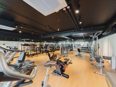 Heller, moderner Fitnessraum mit verschiedenen Trainingsgeräten und Holzfußboden.