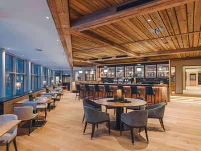 Großer Hotelbarbereich mit Holzdecke, Holzfußboden und Sitzgelegenheiten an Tischen und Bar.