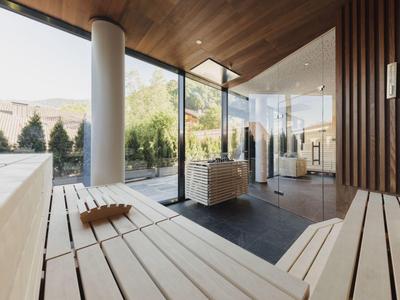 Moderner Saunaraum mit hellen Holzbänken, großen Glasfenstern und Blick auf Außenbereich.