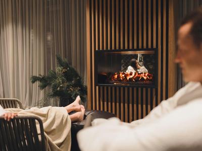 Zwei Menschen entspannen sich vor einem modernen Kamin, warme Beleuchtung, gemütliche Atmosphäre.