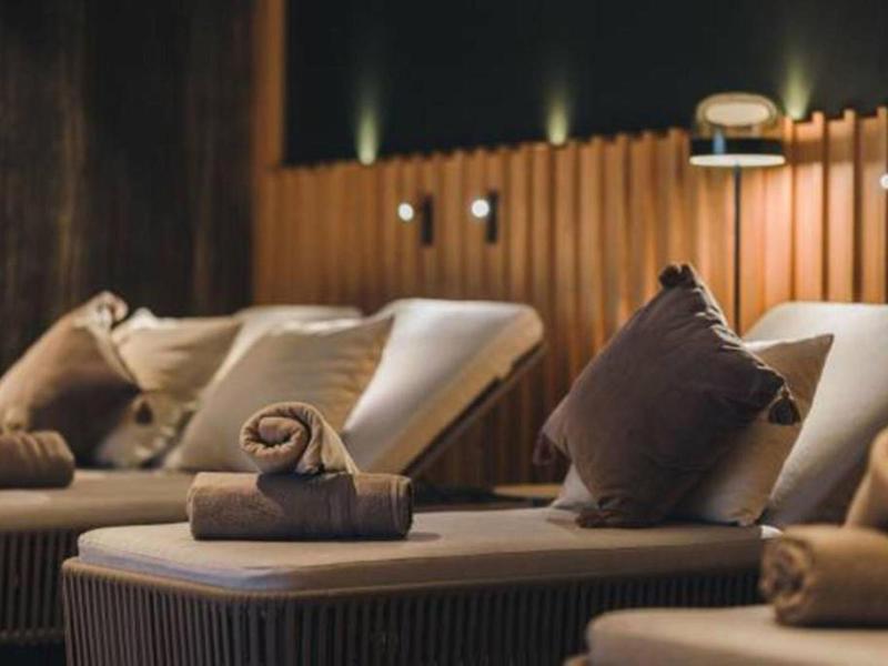 Gemütliche Liegen mit weichen Kissen und gerollten Handtüchern in warm beleuchtetem Wellnessraum.