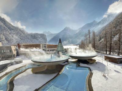 Terme invernali con piscine curve in una valle montuosa innevata.