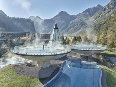 Complesso alberghiero moderno con bagni di vapore e piscina tra montagne e foreste.