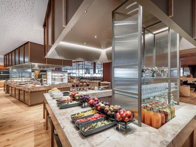 Buffet moderno con frutta fresca, succhi e arredamento elegante in legno e marmo nel ristorante.