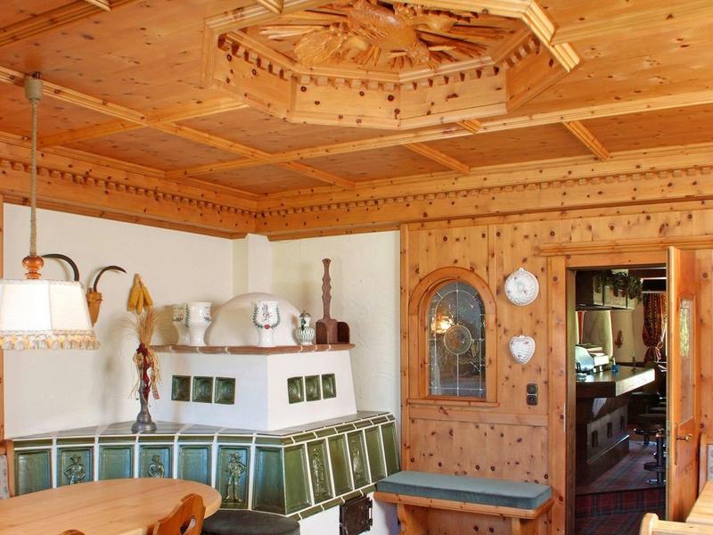 Chambre en bois confortable avec coin salon, poêle en faïence et décor traditionnel.