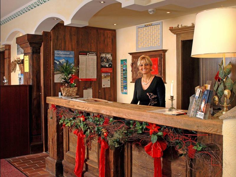 Réception d'hôtel décorée pour Noël avec une employée derrière le comptoir.