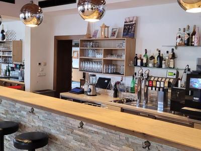 Nowoczesny bar hotelowy z krzesłami, drewnianym ladą i lustrzanymi kulami na suficie.