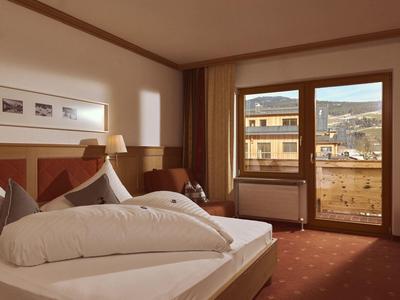 Gemütliches Hotelzimmer mit großem Bett, warmen Holzakzenten und Balkon mit Bergblick.