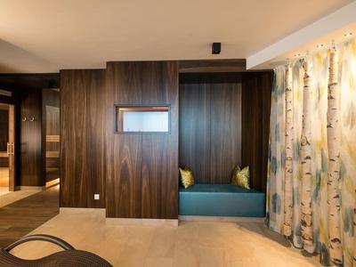 Modern hotel room area with built-in bench, wood-paneled walls, and birch-patterned curtains.