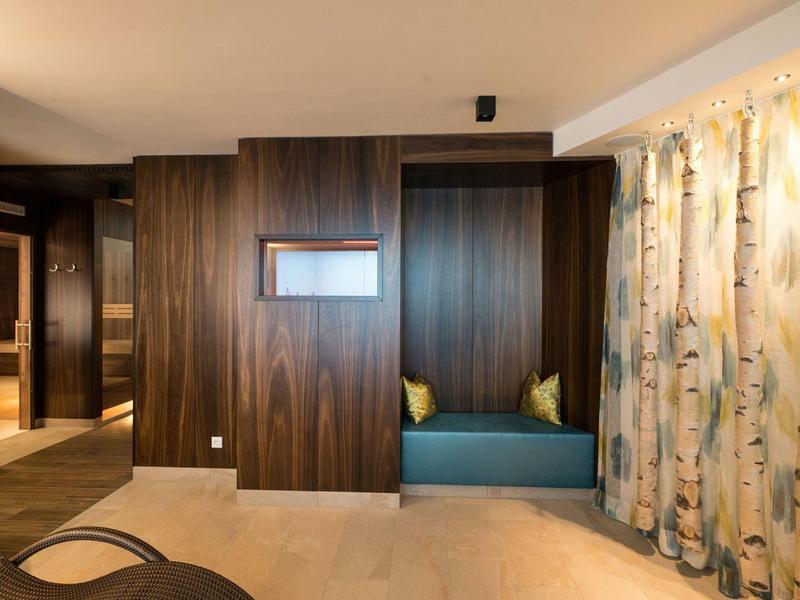 Modern hotel room area with built-in bench, wood-paneled walls, and birch-patterned curtains.
