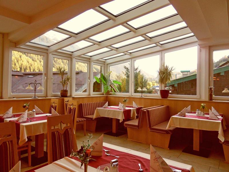 Brightly furnished restaurant area with wooden furniture and large windows.