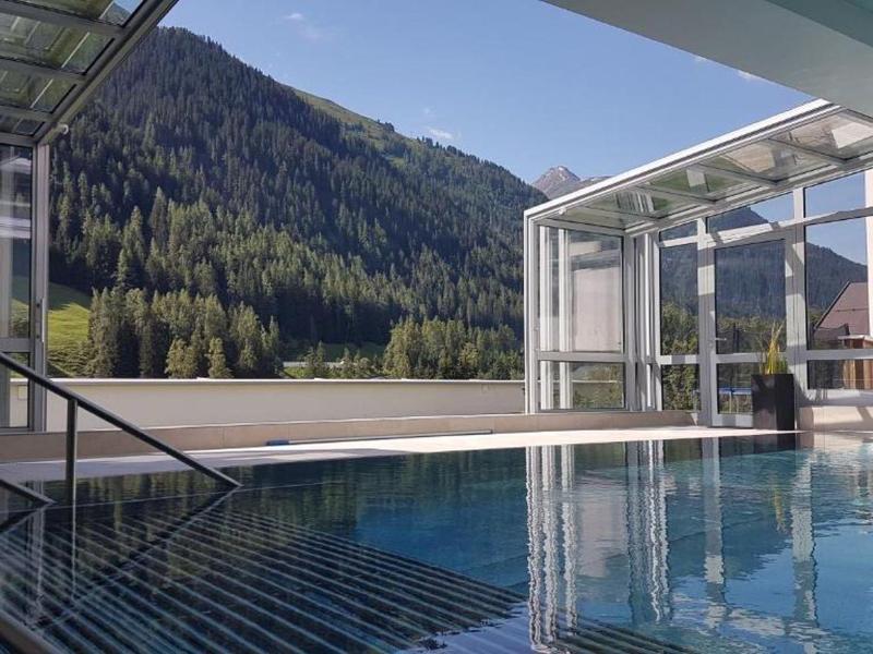 Modern pool with views of forested mountains under clear skies.