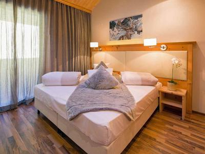 Camera d'hotel accogliente con letto matrimoniale, pavimento in legno e tende alla finestra.