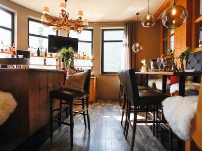 Bar dell'hotel accogliente con bancone in legno, sedie e luce calda.