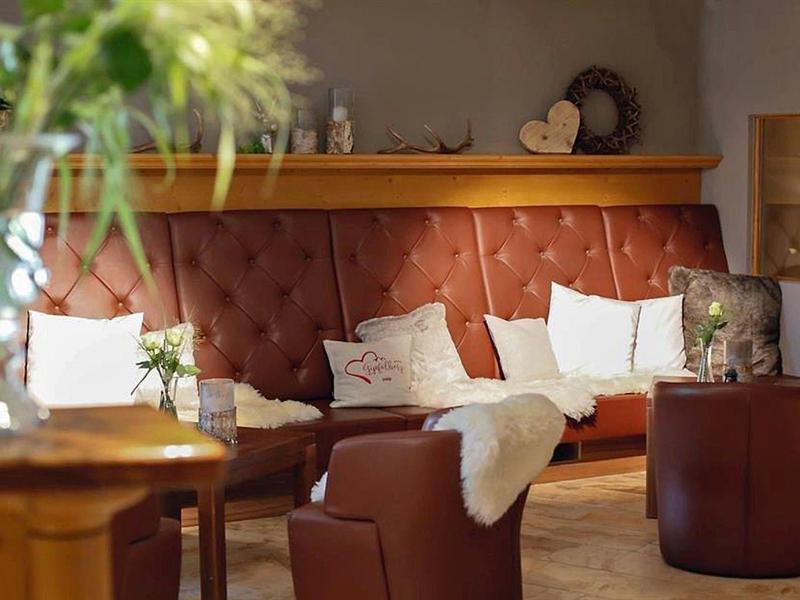 Gemütliche Sitzecke mit braunem Polstersofa, weißen Kissen und warmem Licht.