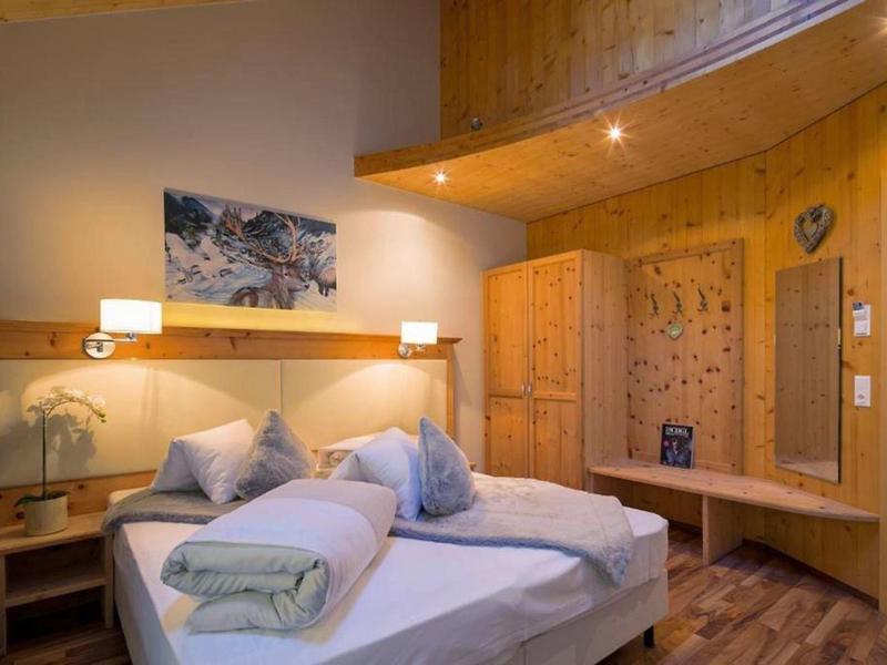 Gemütliches Schlafzimmer mit Holzwänden, Doppelbett, Nachttischen und warmem Licht.