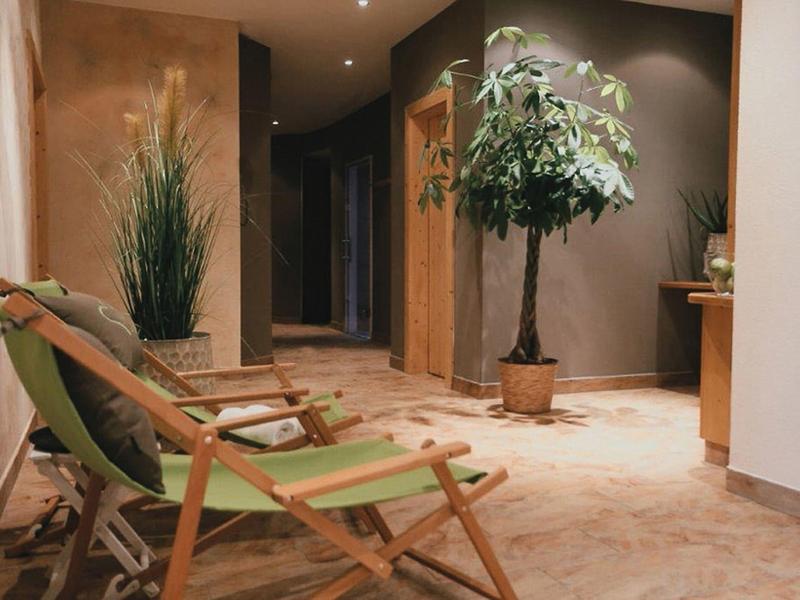 Ein gemütlicher Flur mit zwei grünen Klappstühlen und dekorativen Pflanzen auf braunem Boden.