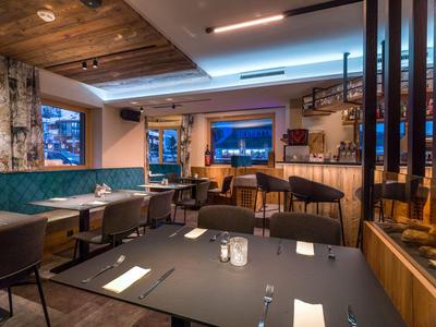 Área de comedor de hotel modernamente amueblada con mesas preparadas y zona de bar.