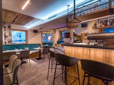 Bar moderno de hotel con paneles de madera, barra y áreas de descanso acogedoras.