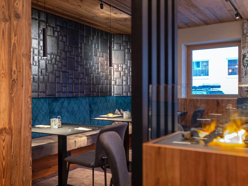 Modernes Restaurant mit Holzwänden, blauen Sitzbänken und dekorativen schwarzen Wandpaneelen.
