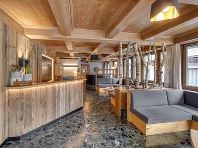 Gezellig hotel lobbygebied met houten meubels en natuurstenen vloer, warm verlicht.