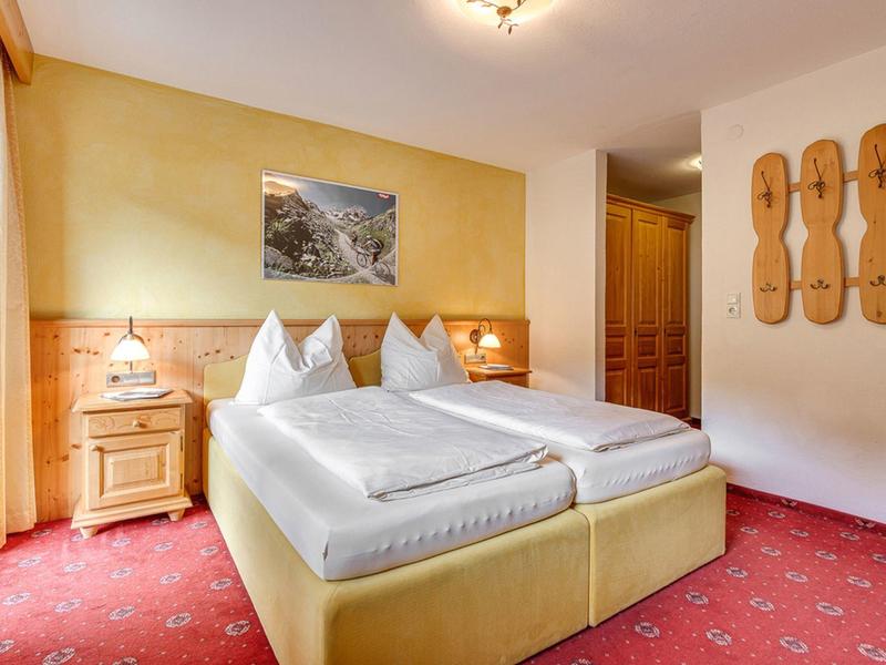 Camera d'hotel luminosa con letto matrimoniale, comodini, moquette e decorazioni murali.