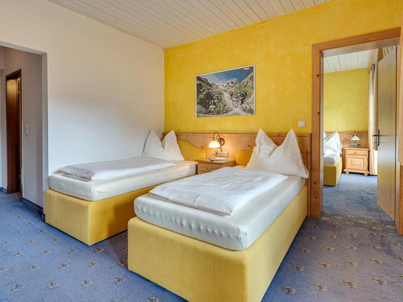 Camera d'hotel con due letti singoli, parete gialla e moquette blu.