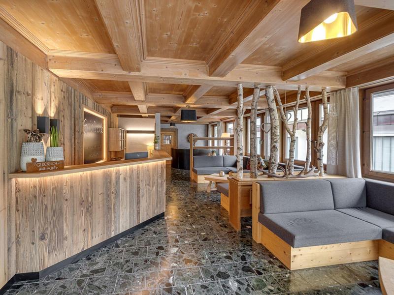 Accogliente area lounge dell'hotel con mobili in legno e pavimento in pietra sotto illuminazione calda.