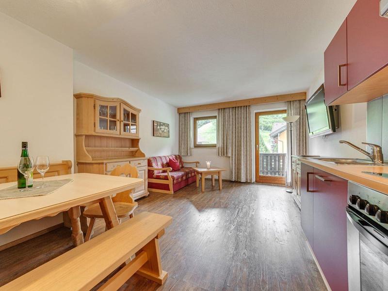 Soggiorno luminoso con mobili in legno, armadi cucina viola, panca e finestra con balcone