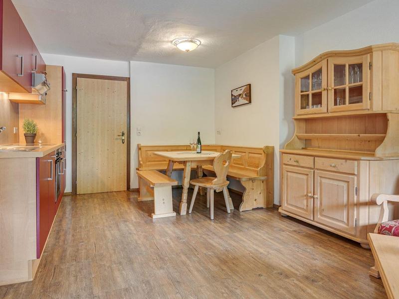 Accogliente zona pranzo con tavolo in legno, panca ad angolo e credenza con luce calda.