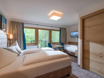 Helles Schlafzimmer mit zwei Betten, großem Fenster, Holztür und moderner Einrichtung.