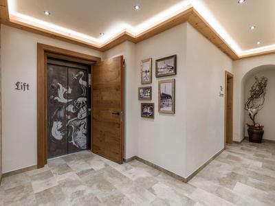 Moderner Hotelflur mit Aufzug und Wandbildern in warm beleuchtetem Ambiente.