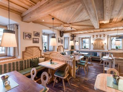 Gemütliches Restaurant mit Holzbalkendecke, Sitzecken und dekorativen Bildern an den Wänden.