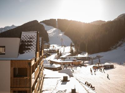 Mountain ski resort with chalets, snow-covered slopes, and people enjoying winter activities.
