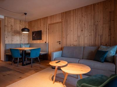 Cozy living room with wooden walls, a gray sofa, blue chairs, and round wooden coffee tables.