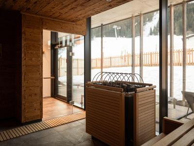 Cozy wooden sauna room with glass door showing snowy outdoor landscape.