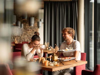 Dva lidé sedící v moderní restauraci si užívají nápoje a občerstvení.