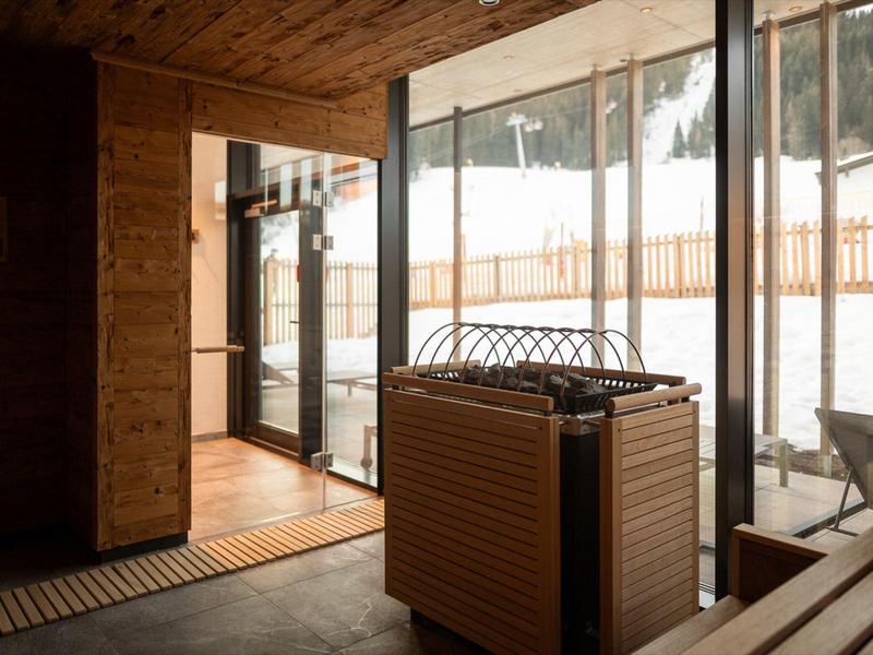 Cozy wooden sauna room with glass door showing snowy outdoor landscape.