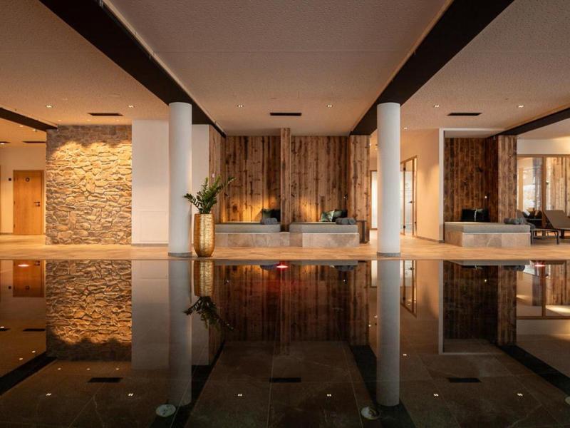 Indoor pool area with warm lighting, wooden walls, and modern design elements.