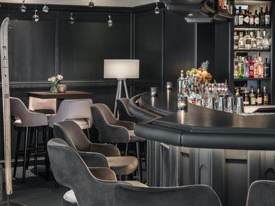 Bar de hotel elegante con sillones cómodos, barra y iluminación estilizada en diseño moderno.