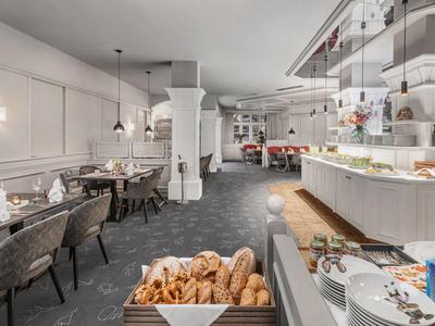 Buffet moderno de desayuno con cesta de pan y zona de estar en un restaurante de hotel.