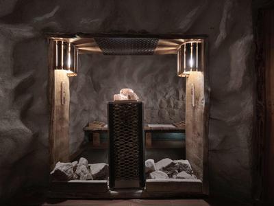 Sauna con paredes de piedra, luz tenue y piedras calientes en el centro para relajación