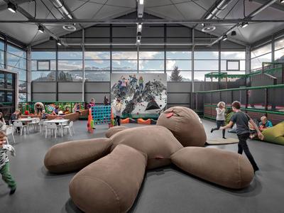 Amplio espacio interior con zona infantil, pufs y un enorme peluche.