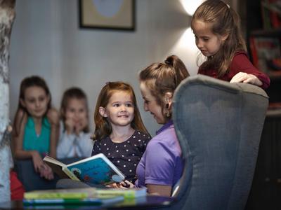 Niños leen juntos en una habitación acogedora con libros y sillas cómodas.