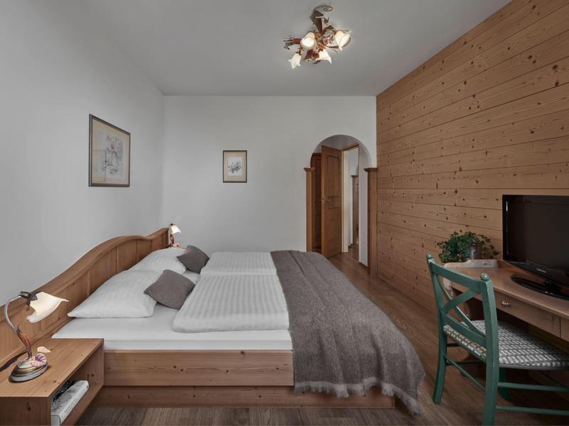 Habitación de hotel sencilla con muebles de madera, cama doble y escritorio con televisor.