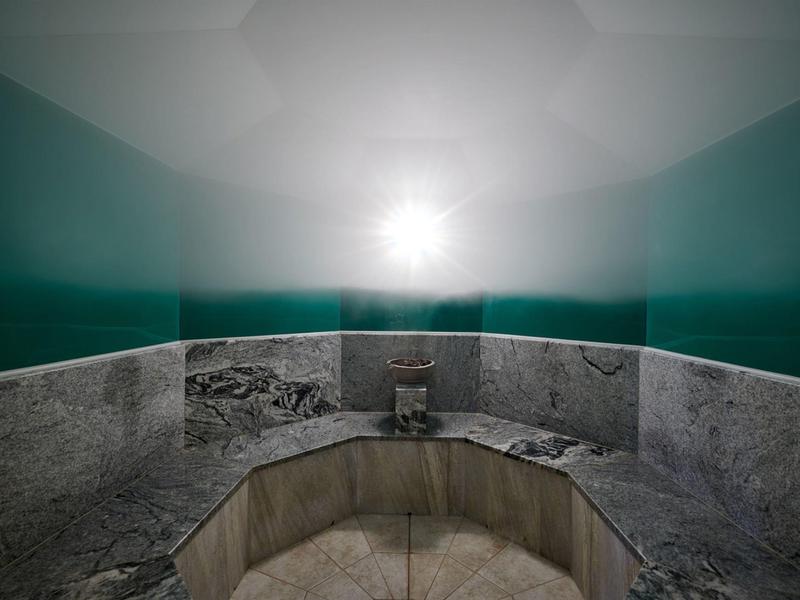 Baño de vapor con paredes neblinosas y área de asiento de baldosas de mármol.